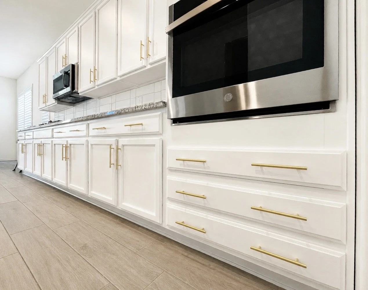 White painted kitchen cabinets with gold pulls and stainless appliances