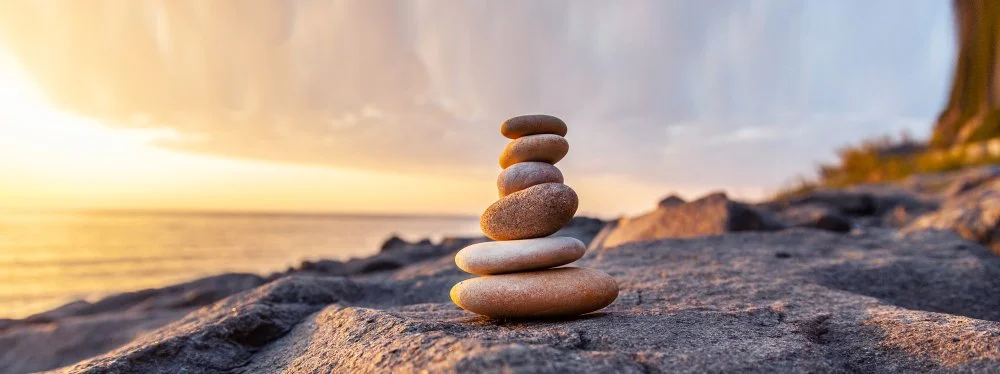 Balanced stones beside the water at sunset