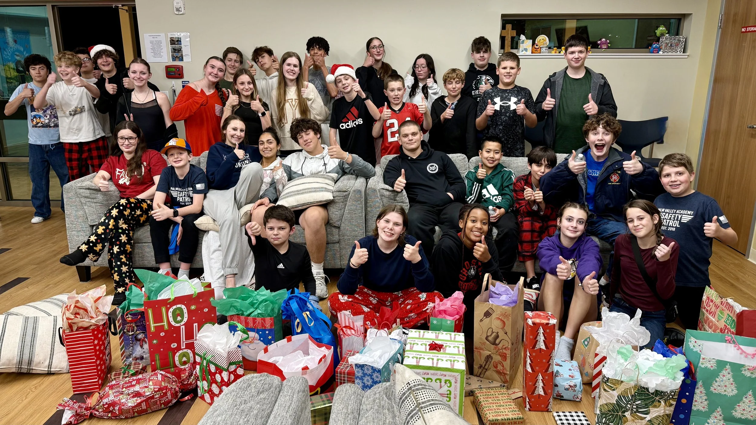 .A picture of middle school and high school youth sitting in front of a couch at their Christmas party.