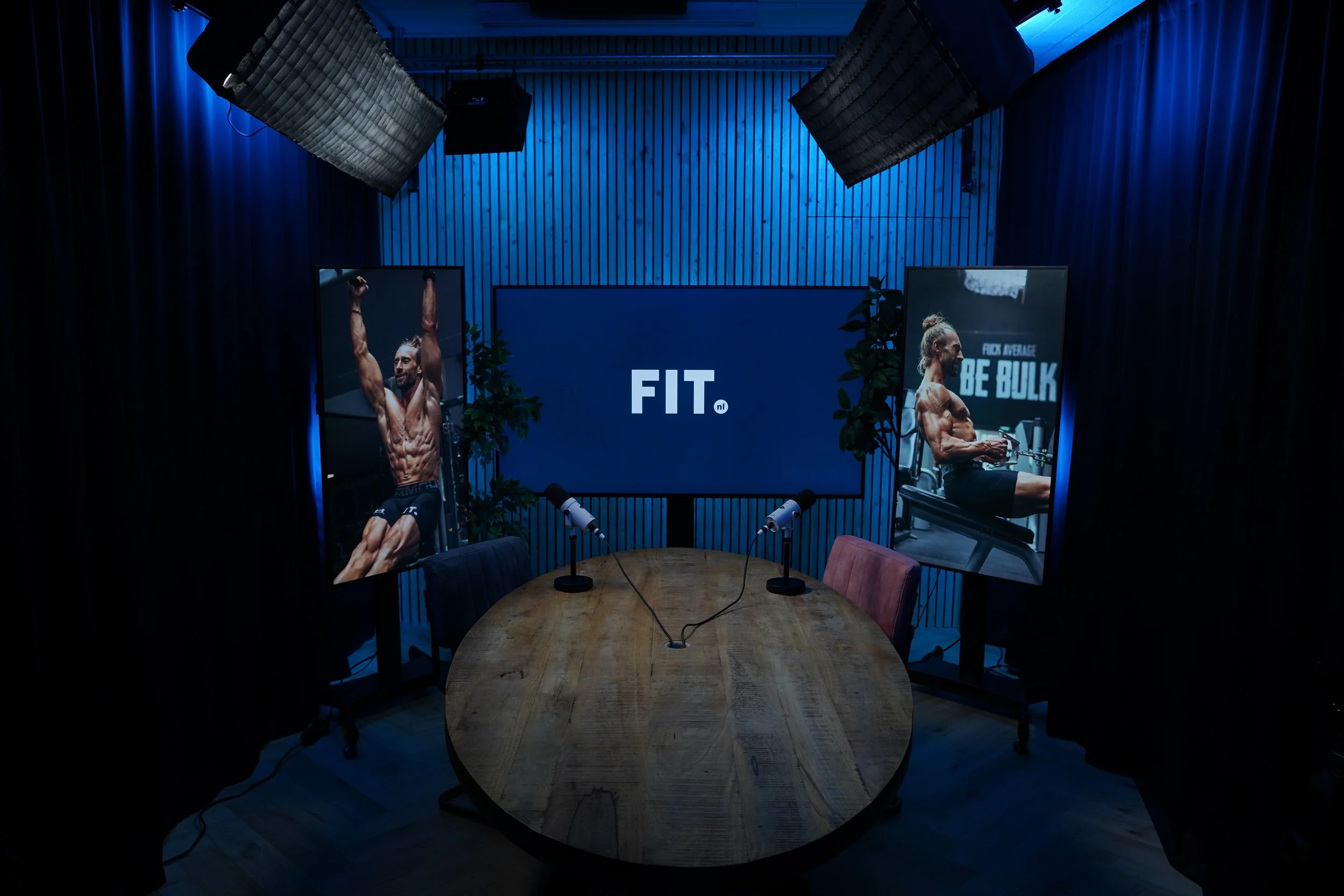 Opnametafel met twee microfoons en het Kudo Media logo op het 85 inch scherm