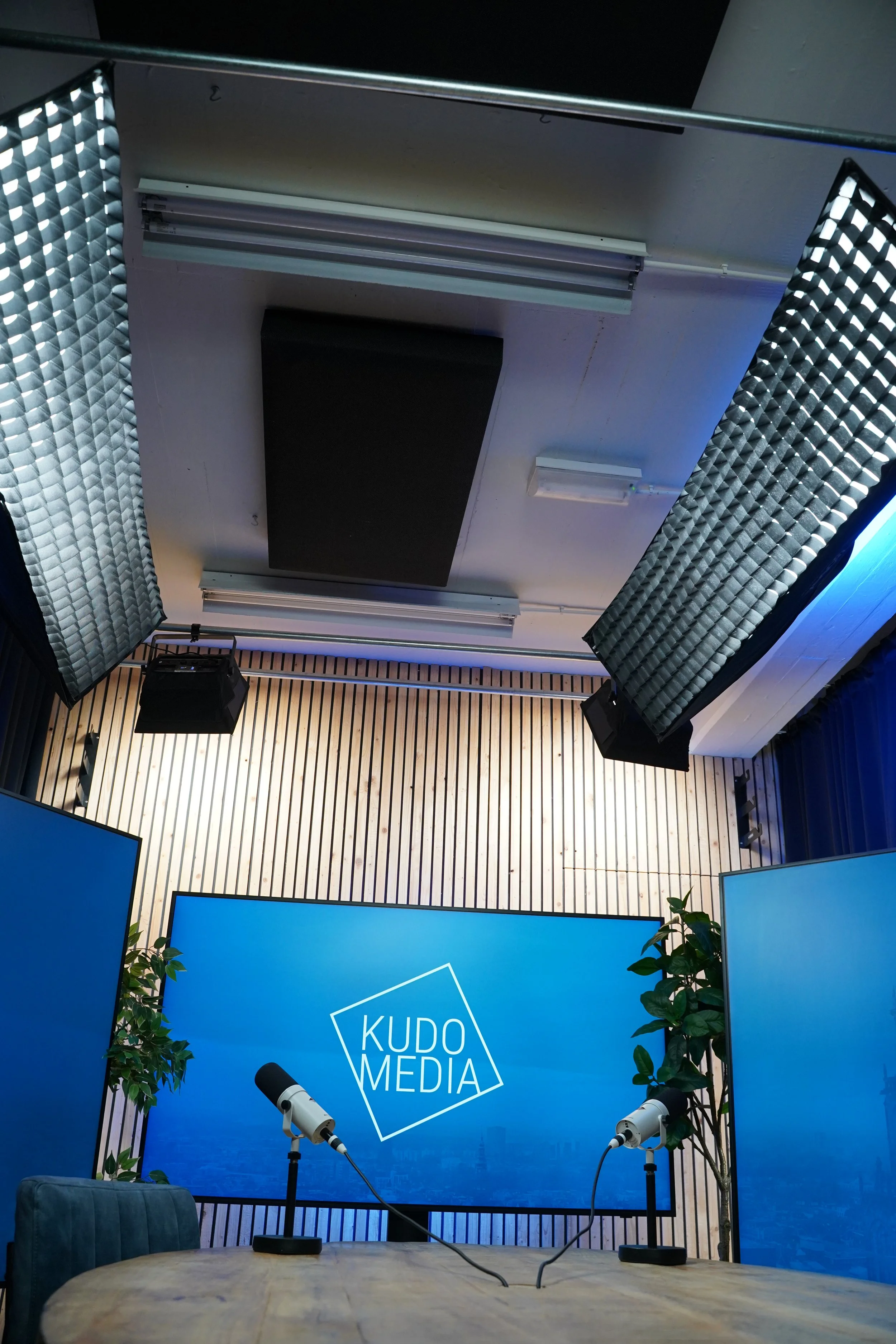 Studioverlichting met softboxen en akoestische plafondpanelen boven de podcasttafel