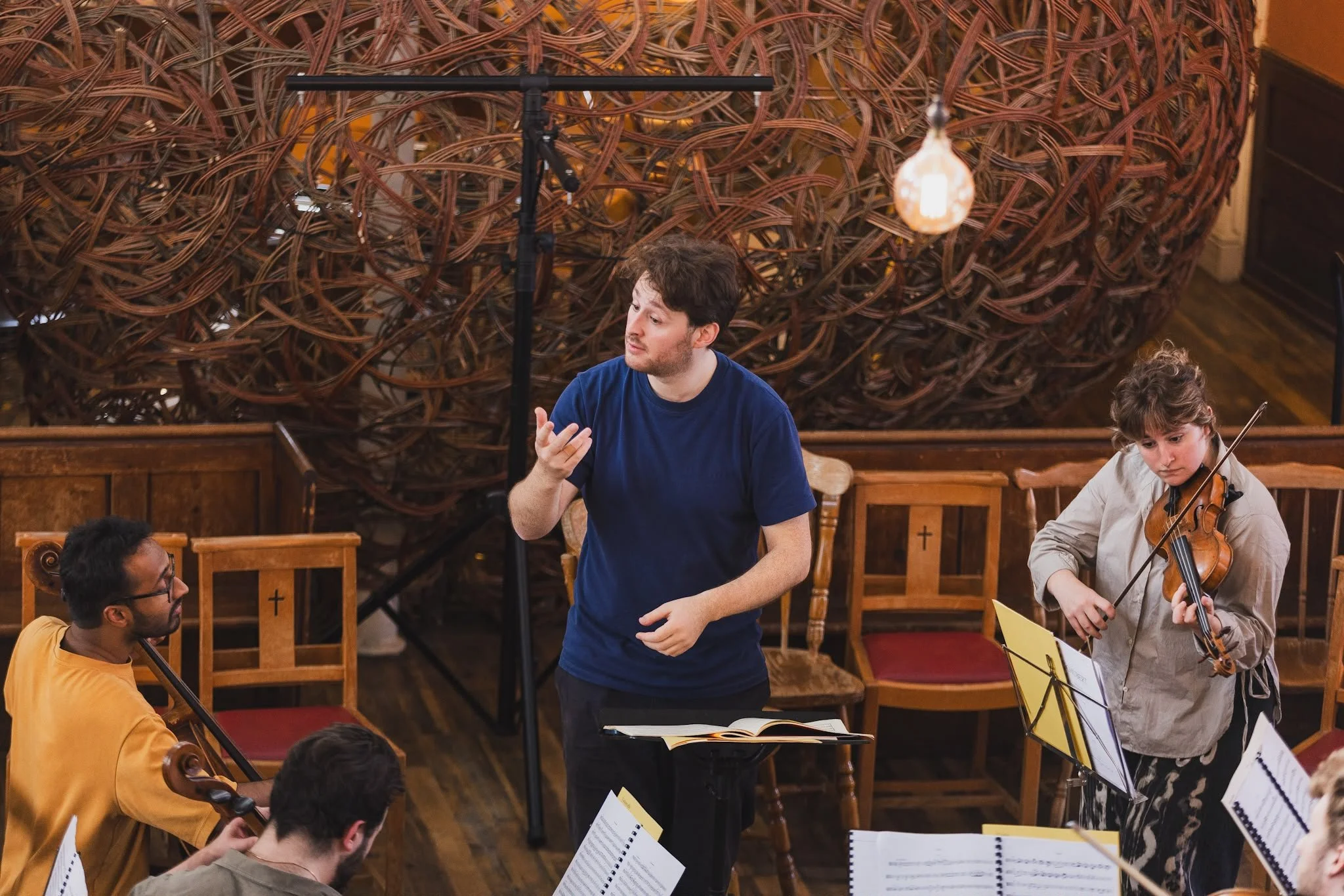 Conductor and string players working together in rehearsal