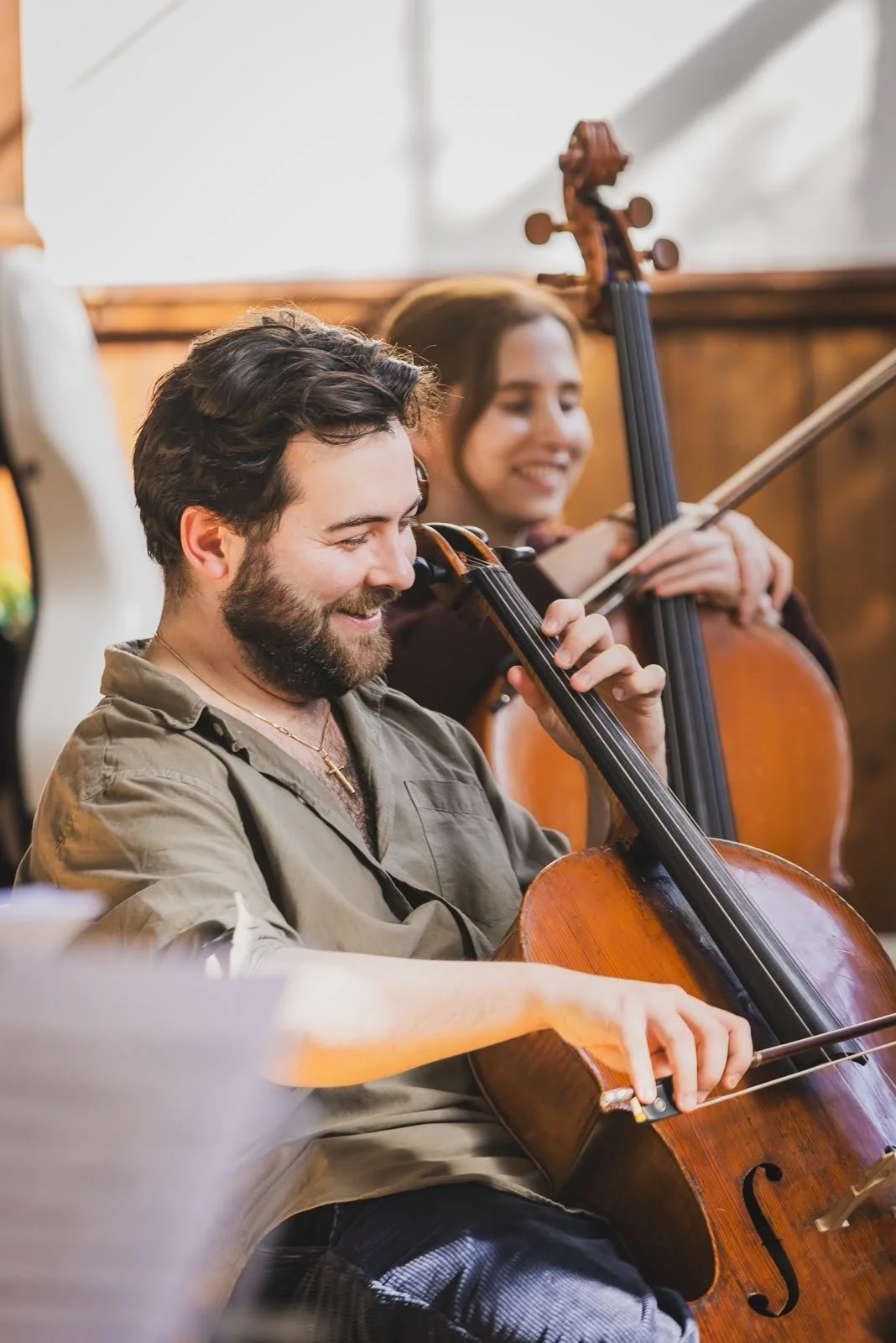 Cellists sharing a smile during rehearsal