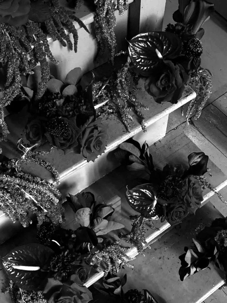 Burgundy amaranth, anthurium and roses cascading down a stairway, in black and white