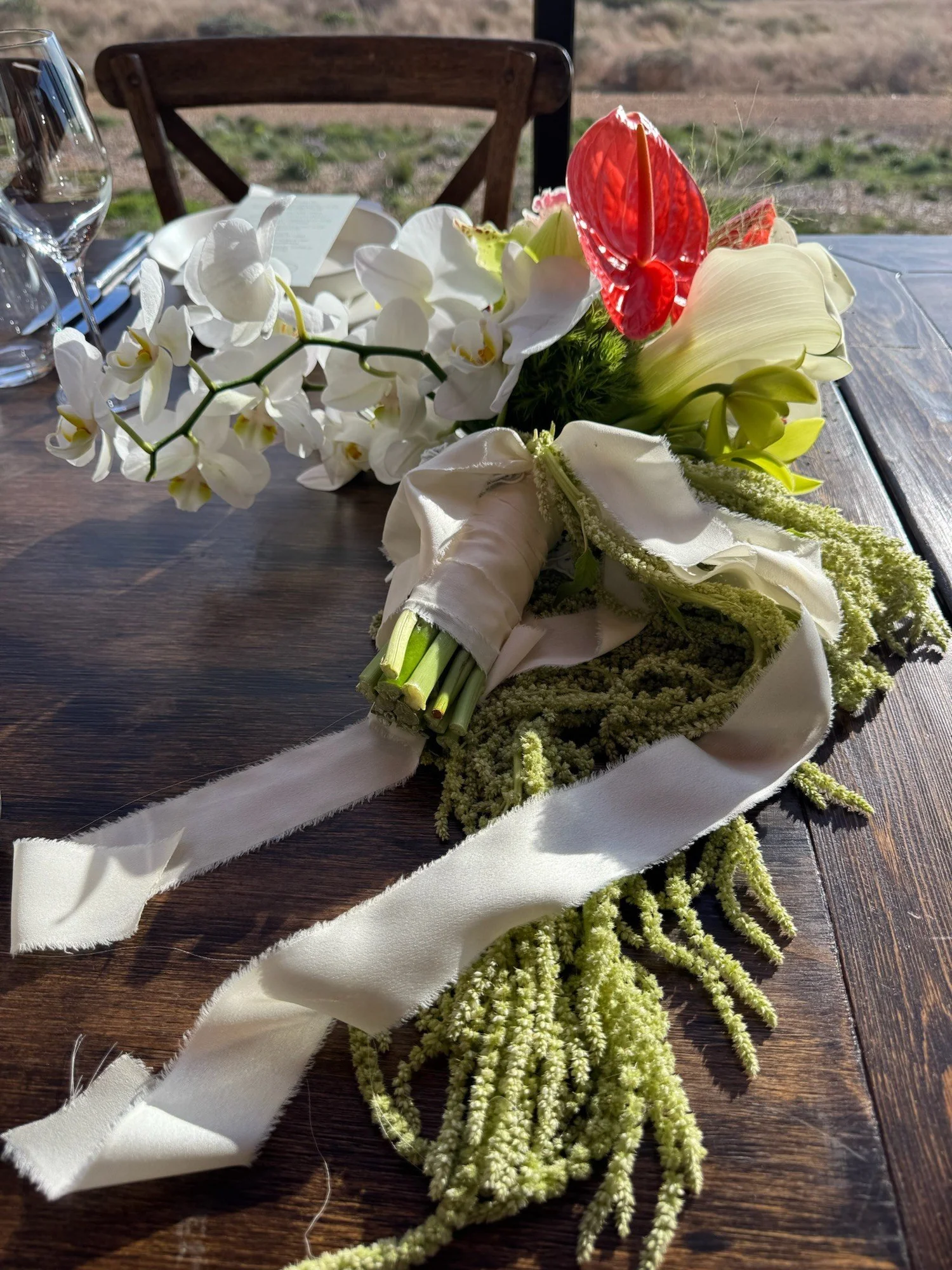 Bridal bouquet with silk ribbon and hanging amaranthus resting on the reception table