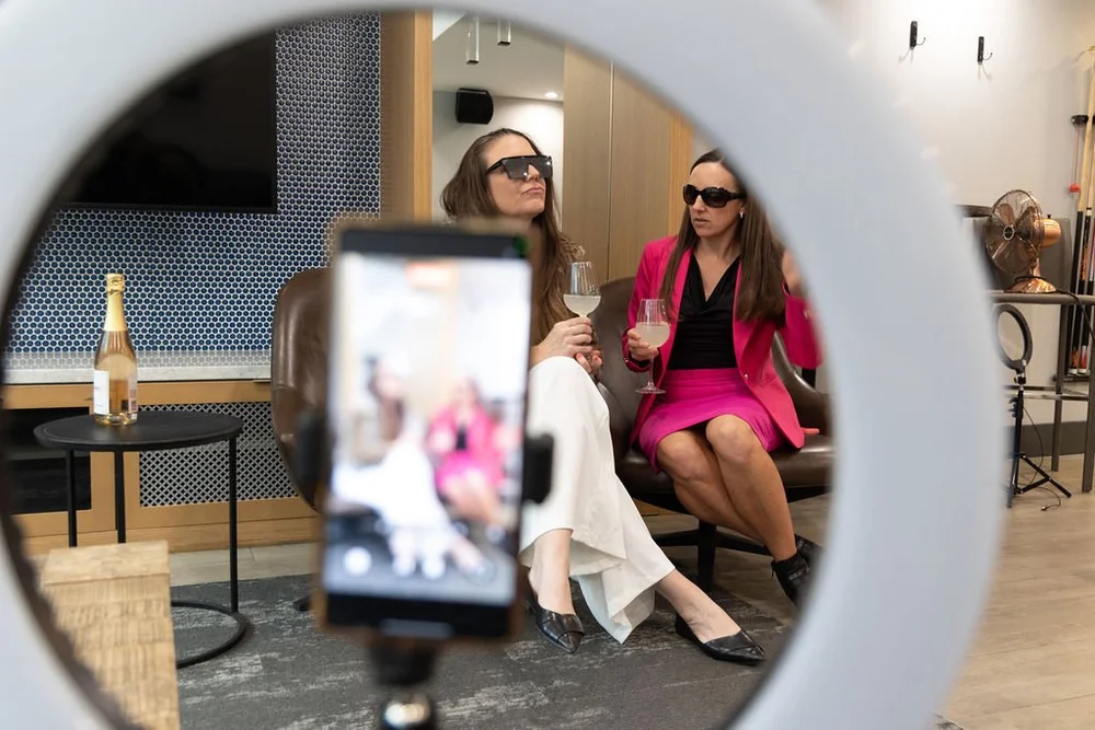 Two attendees filming a video, seen through a ring light