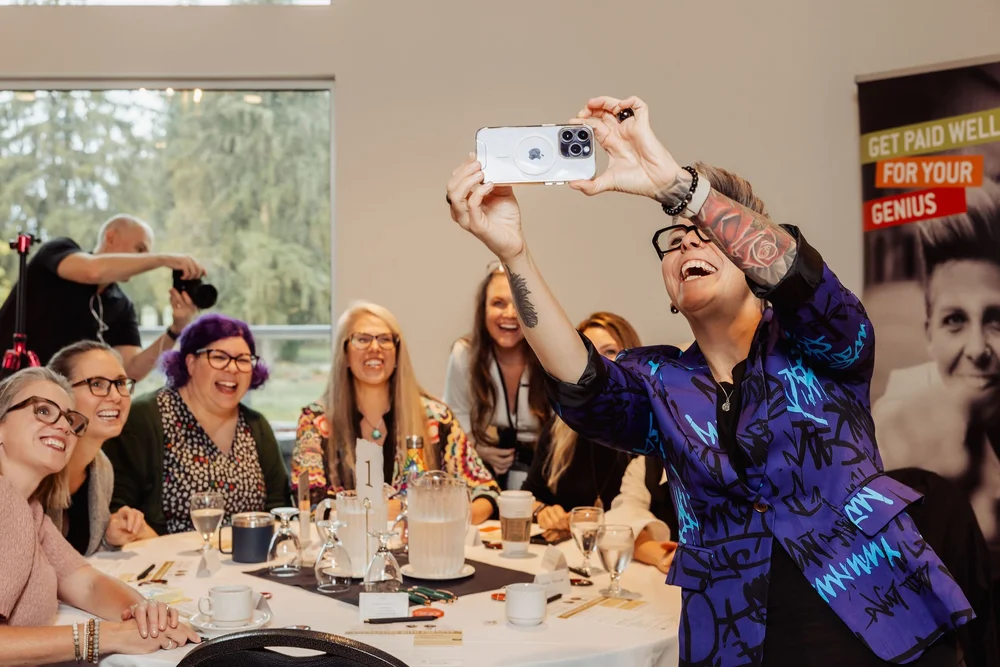 A table of guests and the featured speaker taking a selfie at a Female Forward Collective breakfast
