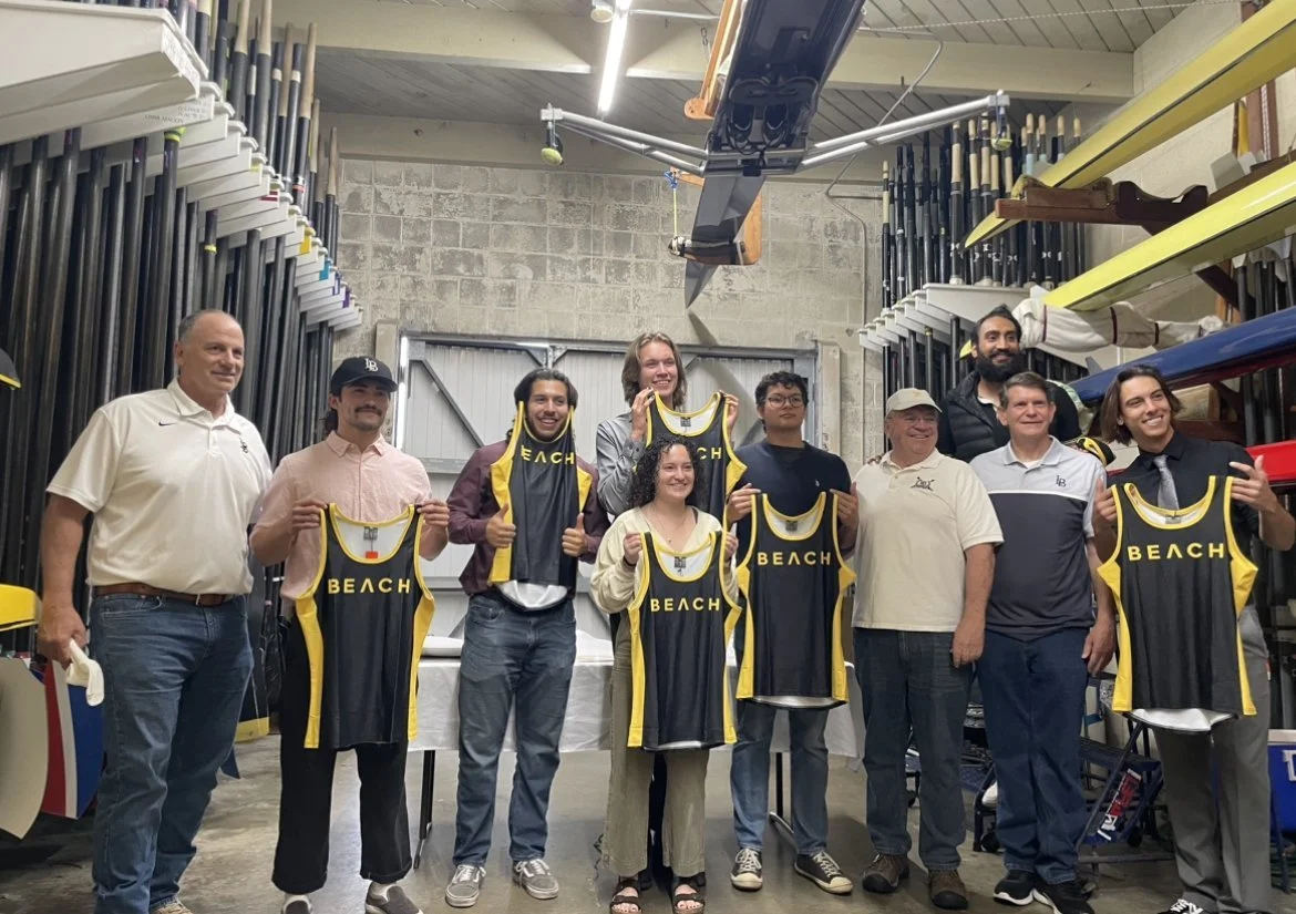 Novices pose with their new shirts beside coaches.
