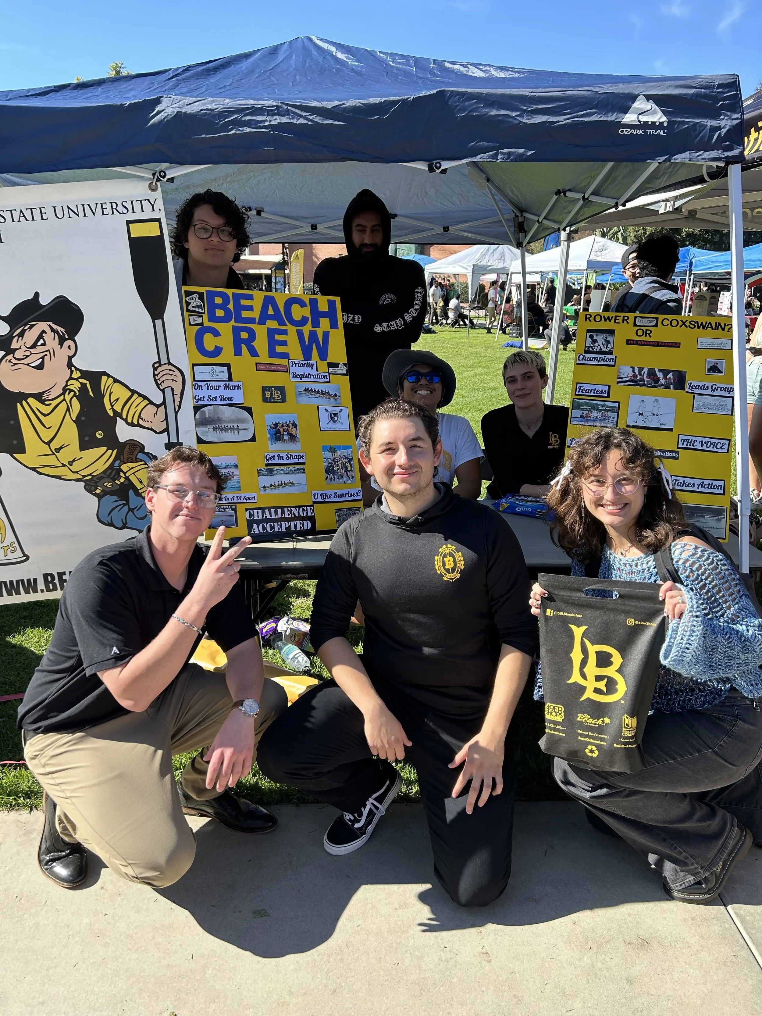 First Photo: Men’s and Women’s Crew members pose in front of their Week of Welcome Booth. 
