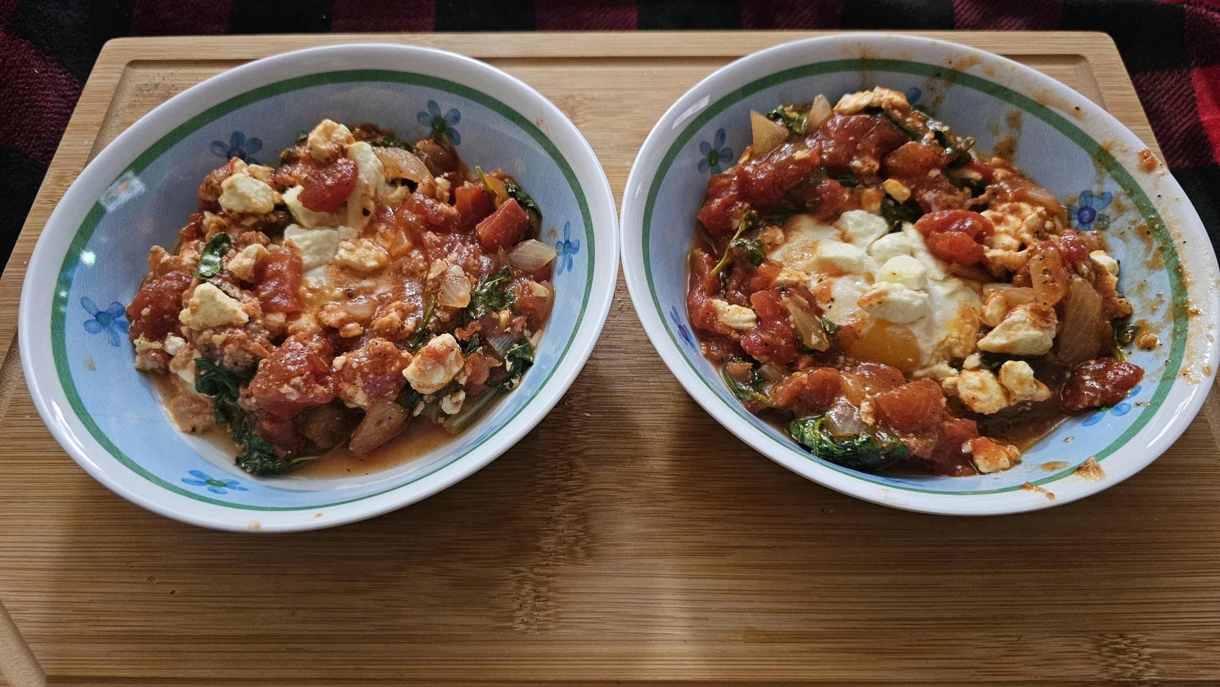 Two eggs baked in red tomato sauce with white feta cheese in a rustic skillet.