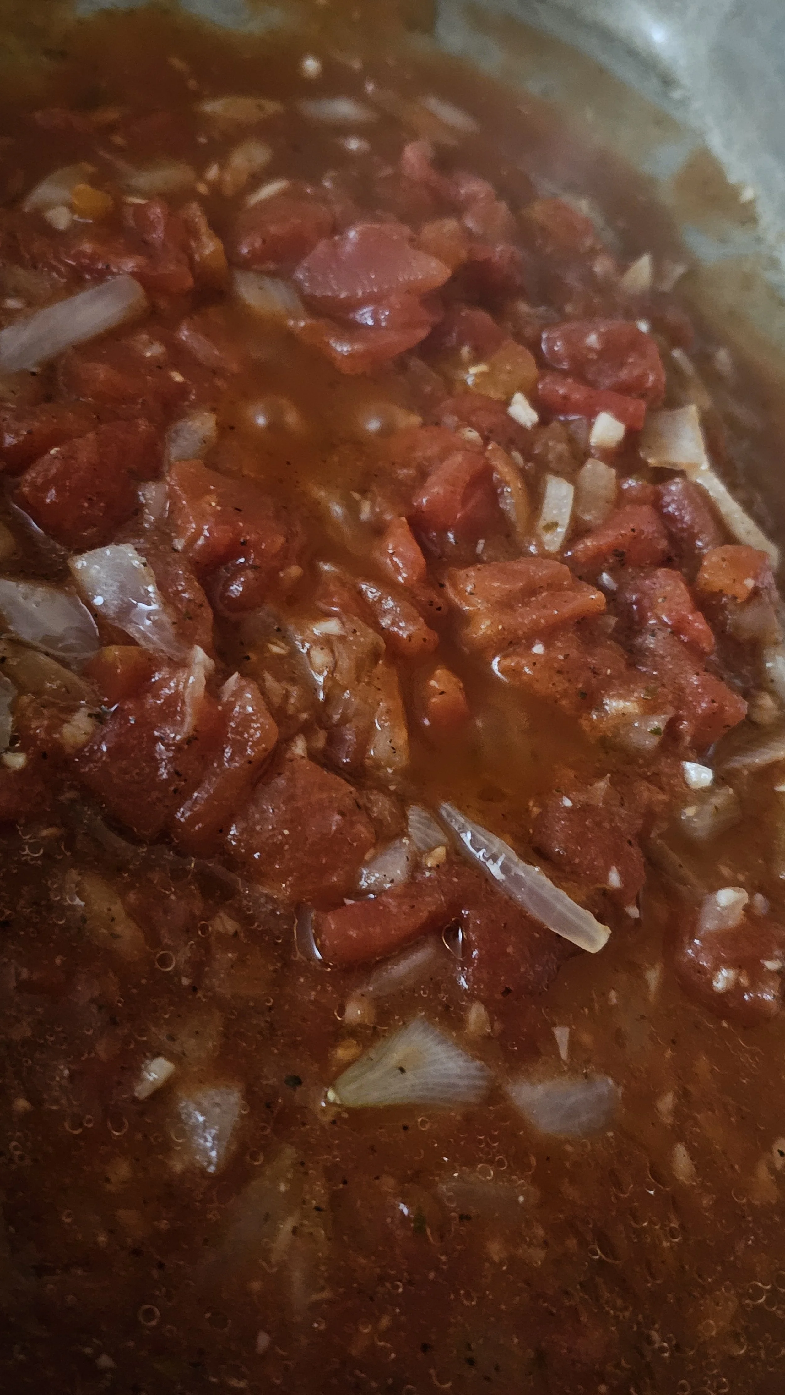 Close-up of vibrant red tomato sauce bubbling with fresh onions and garlic.