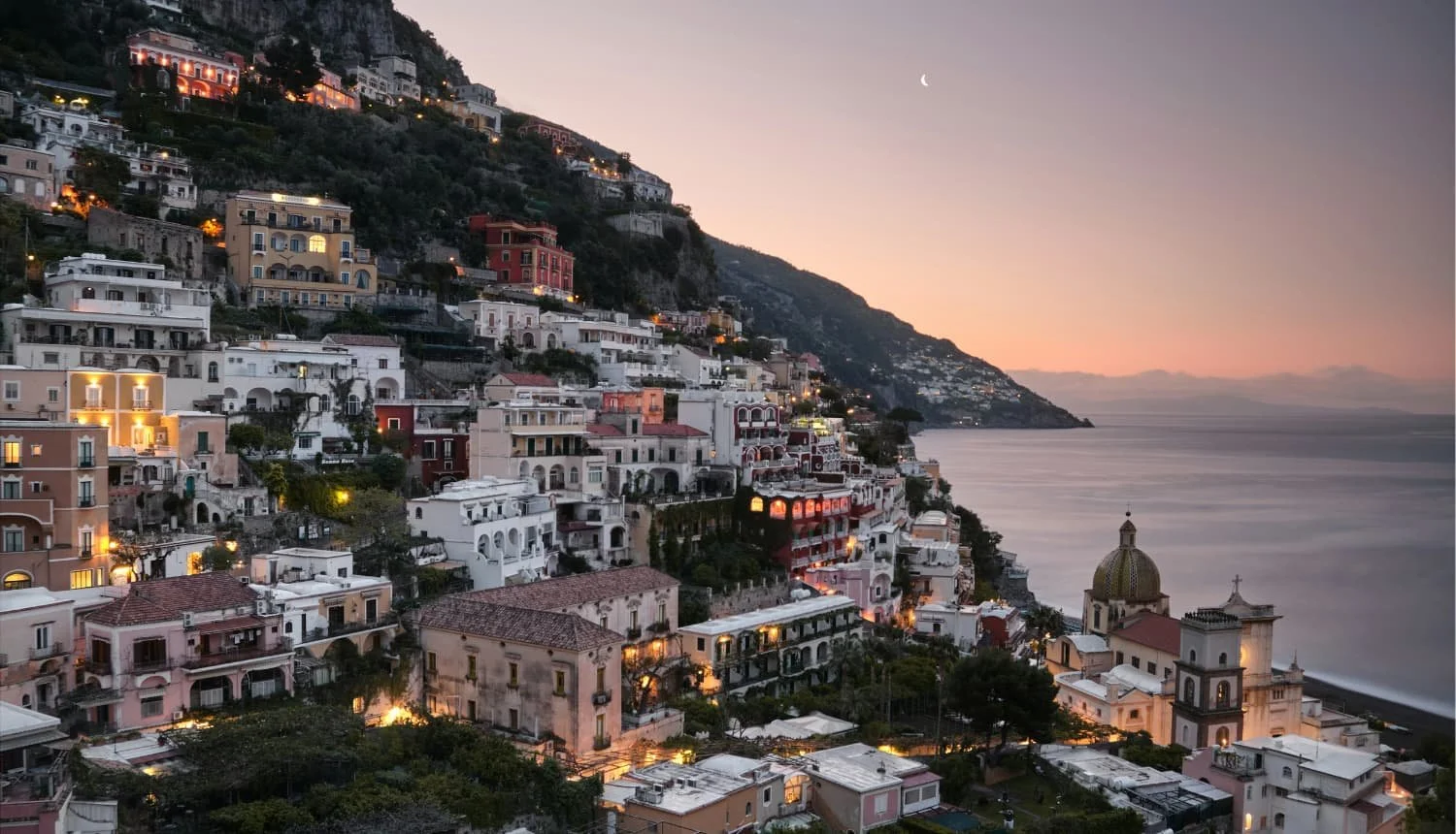 Pastel cliffside houses of the Amalfi Coast stacked above the sea in warm late-afternoon light