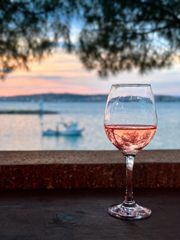 A glass of Côtes de Provence rosé on a terrace table above the Mediterranean