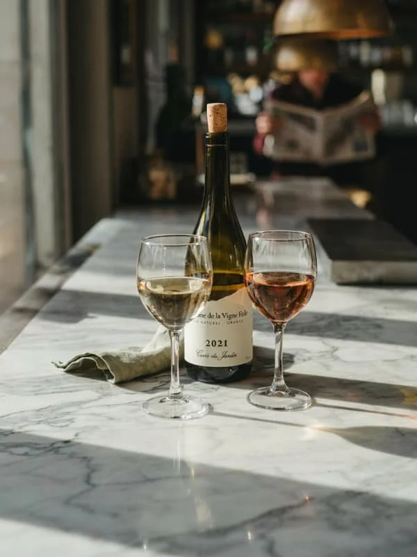 Two glasses of natural wine on a marble table in a Paris wine bar