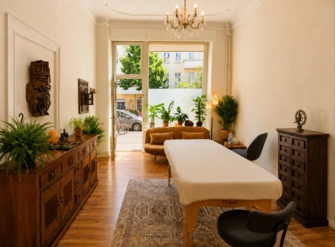 André’s bodywork room at Satori Institute in Berlin-Friedrichshain, with tall windows, plants, sofa and treatment table