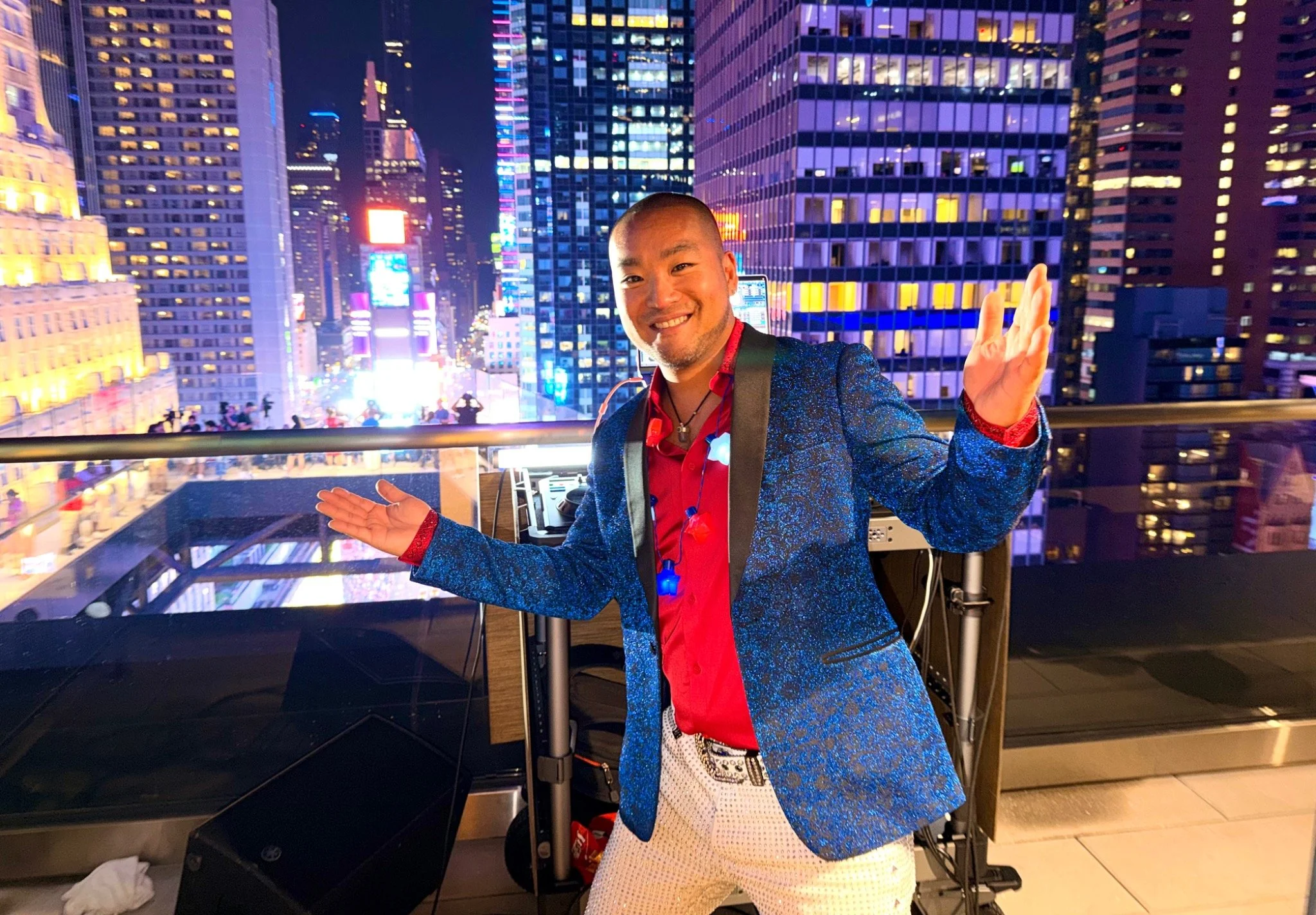 DJ Washburn in a blue jacket overlooking Times Square at night