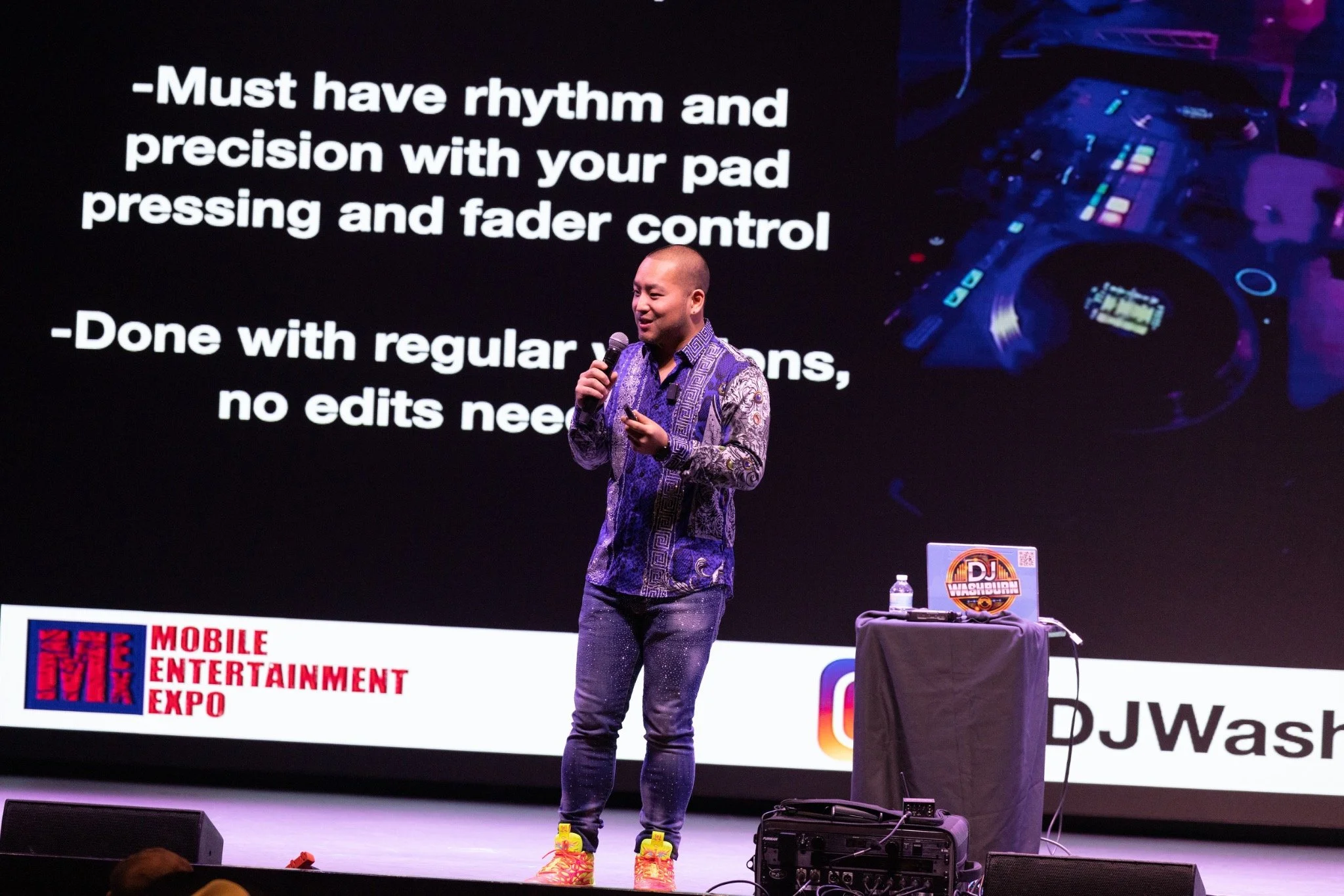 DJ Washburn presenting on stage at Mobile Entertainment Expo with a microphone