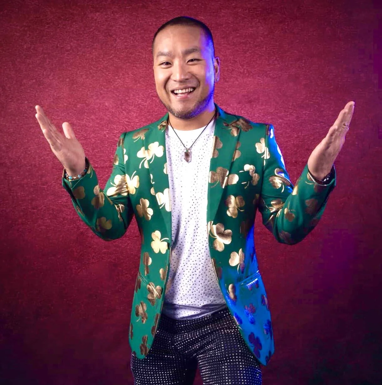 DJ Washburn smiling with open arms in a green and gold shamrock jacket