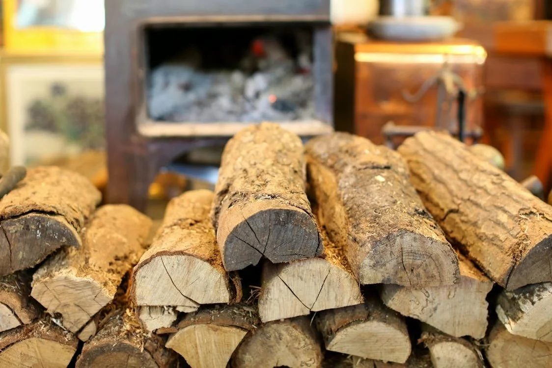 Firewood stacked near a cozy cabin with a campfire