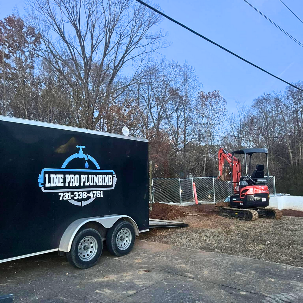 Line Pro Plumbing trailer and mini excavator on a job site in Henry County, TN