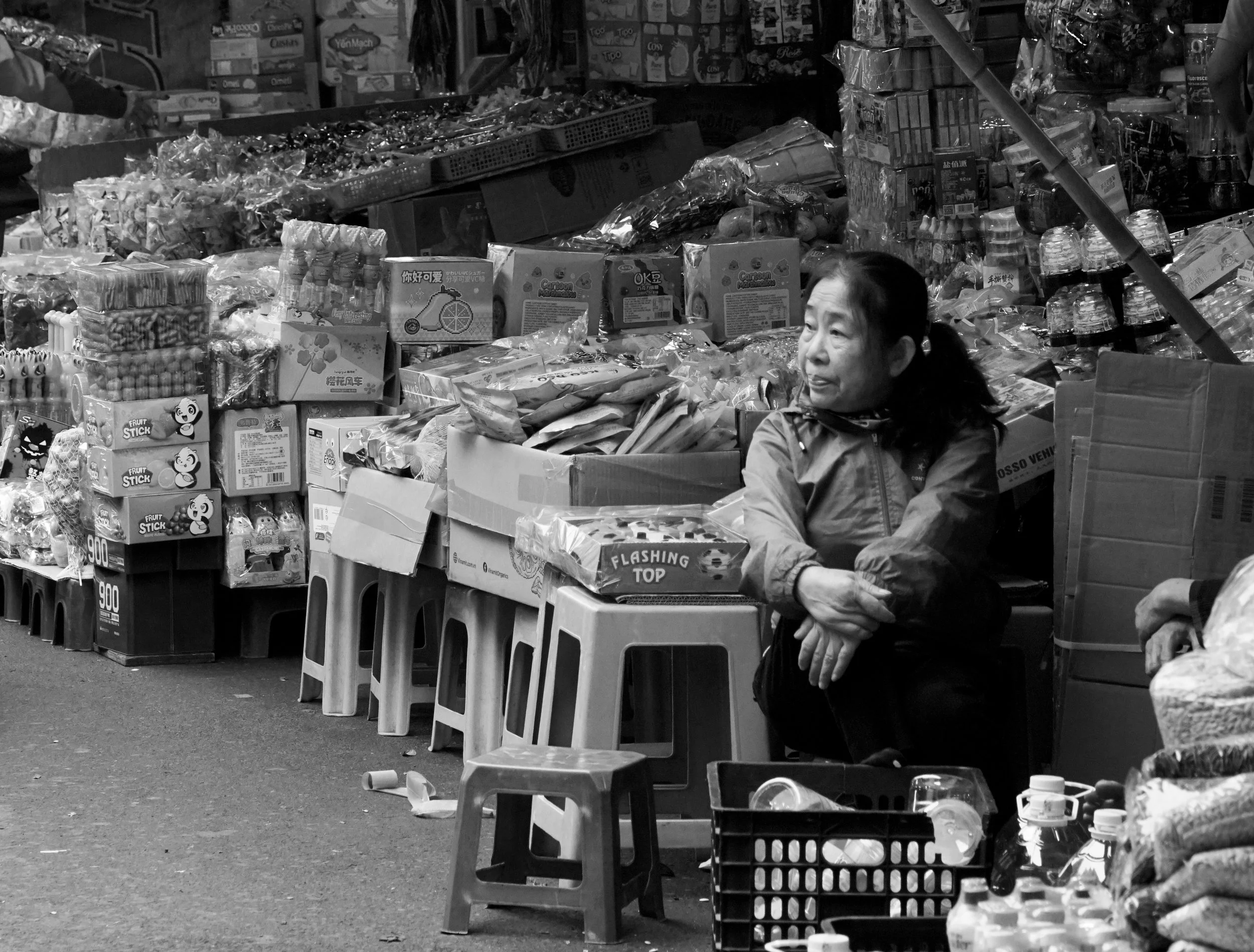 A vendor surrounded by produce at a market, photograph by Frank Díaz