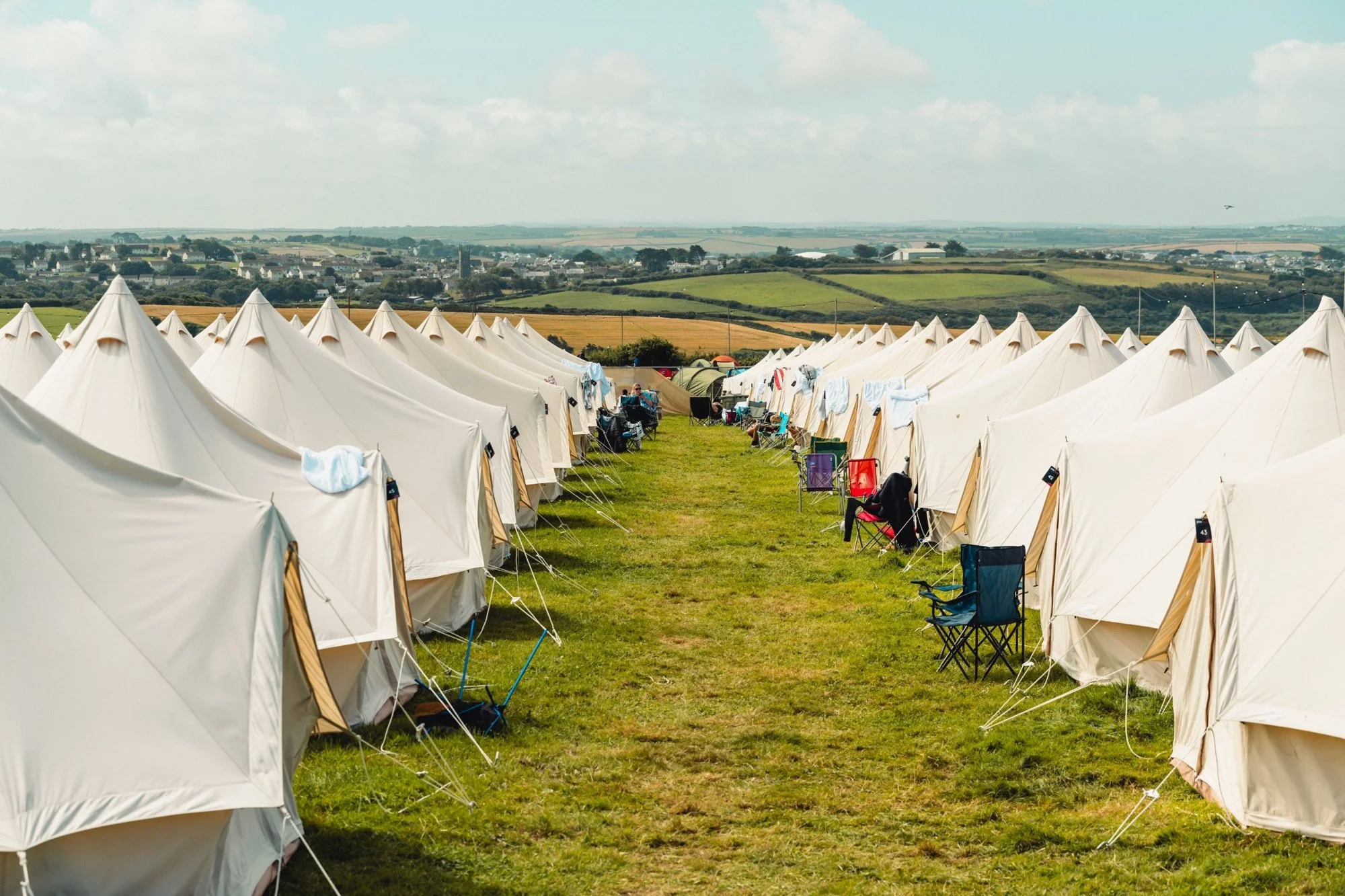 Rows of bell tents laid out in straight lines across a festival campsite