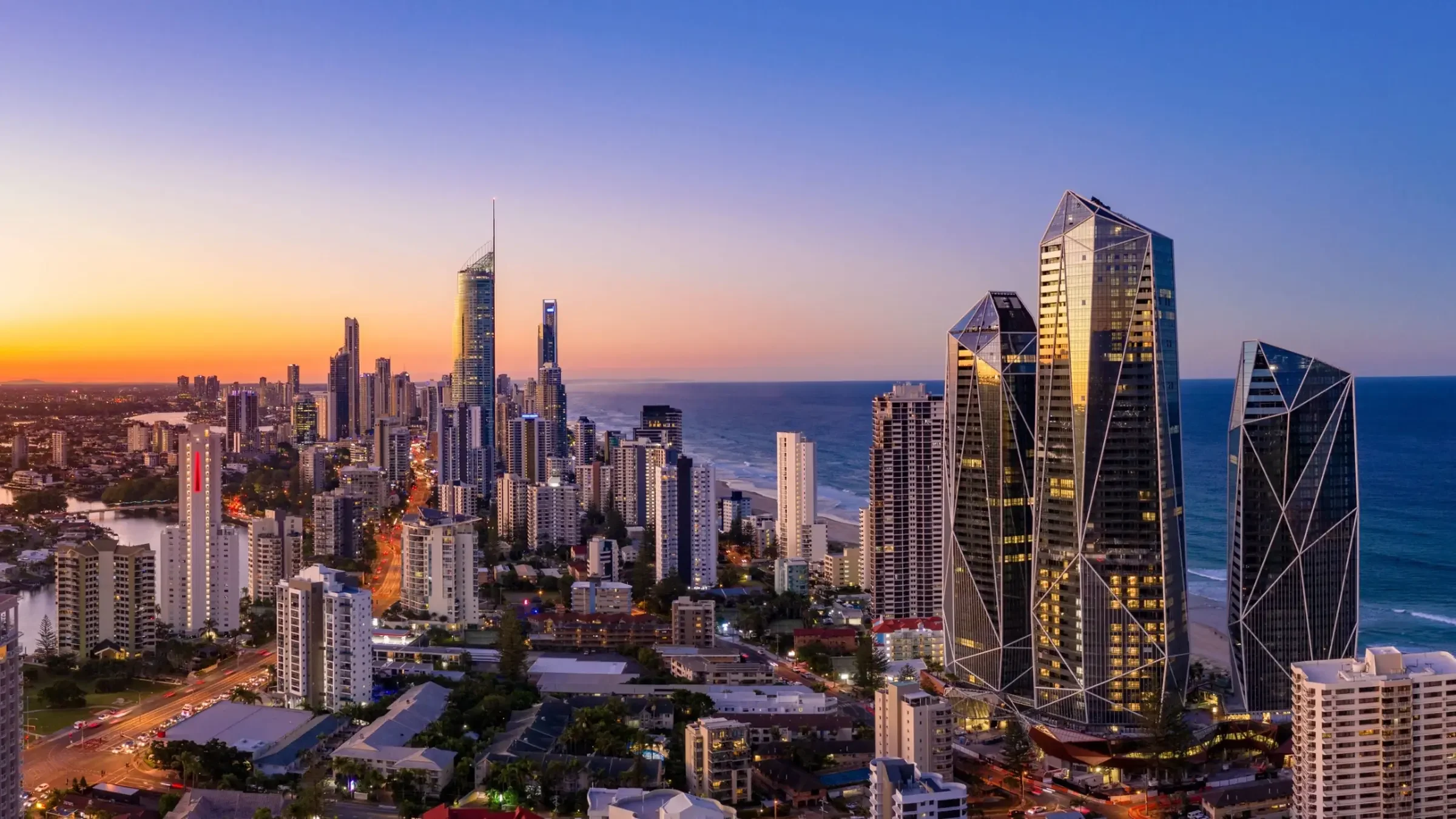 Coastal Australian high-rise accommodation district at sunset, the kind of going-concern hospitality assets owners refinance to release equity without selling