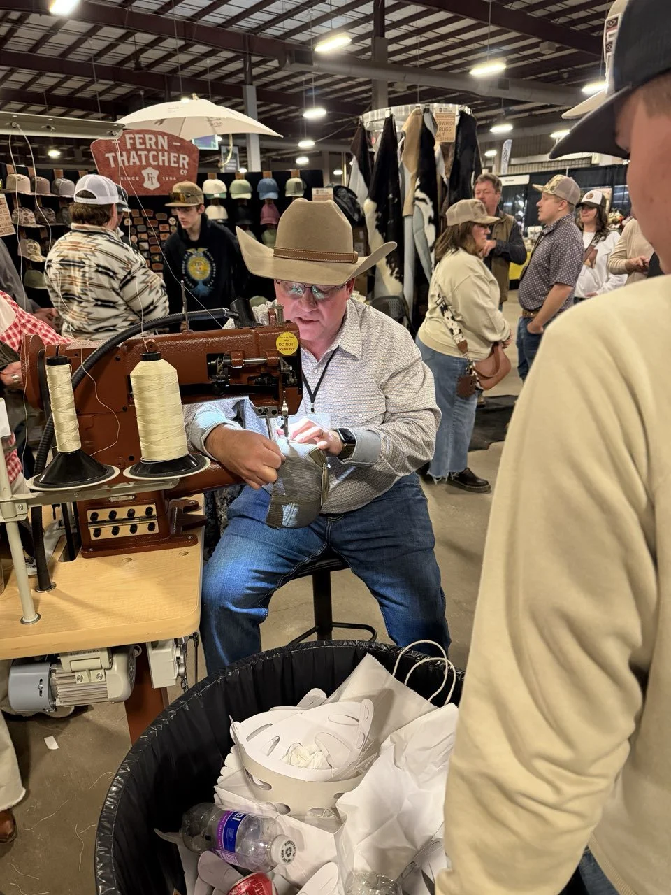 A leatherworker at his sewing machine in a farm show booth