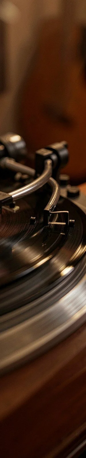 Close-up of a turntable tonearm on a spinning vinyl record