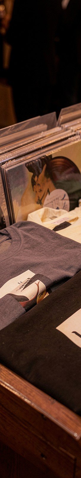 Vinyl records and folded band T-shirts on a merch table
