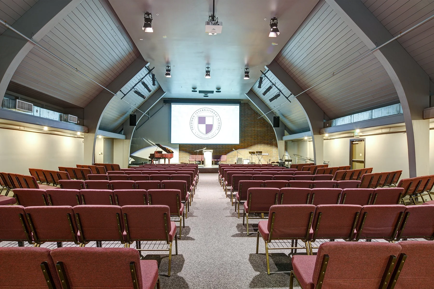Solomon International School auditorium with the school crest on screen