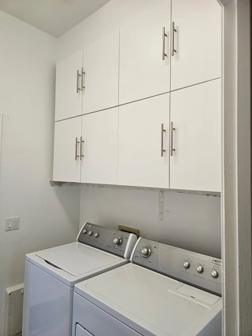 White wall cabinets installed above a washer and dryer in Phoenix