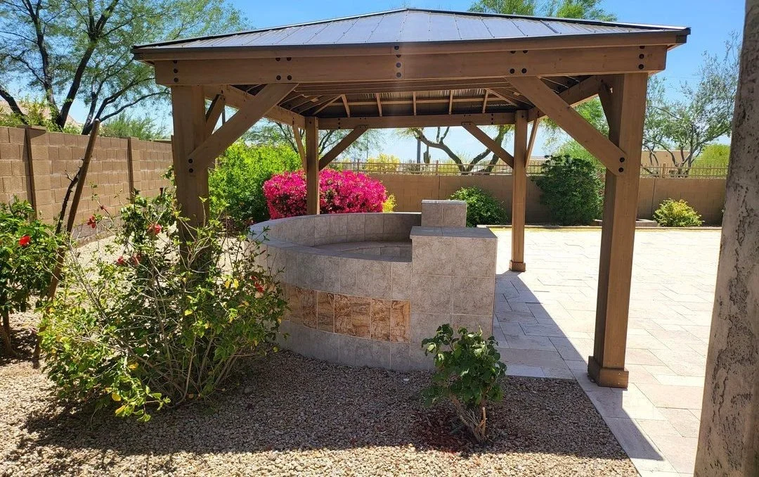 Wood gazebo installed over a stone fire pit seating area in a Phoenix backyard