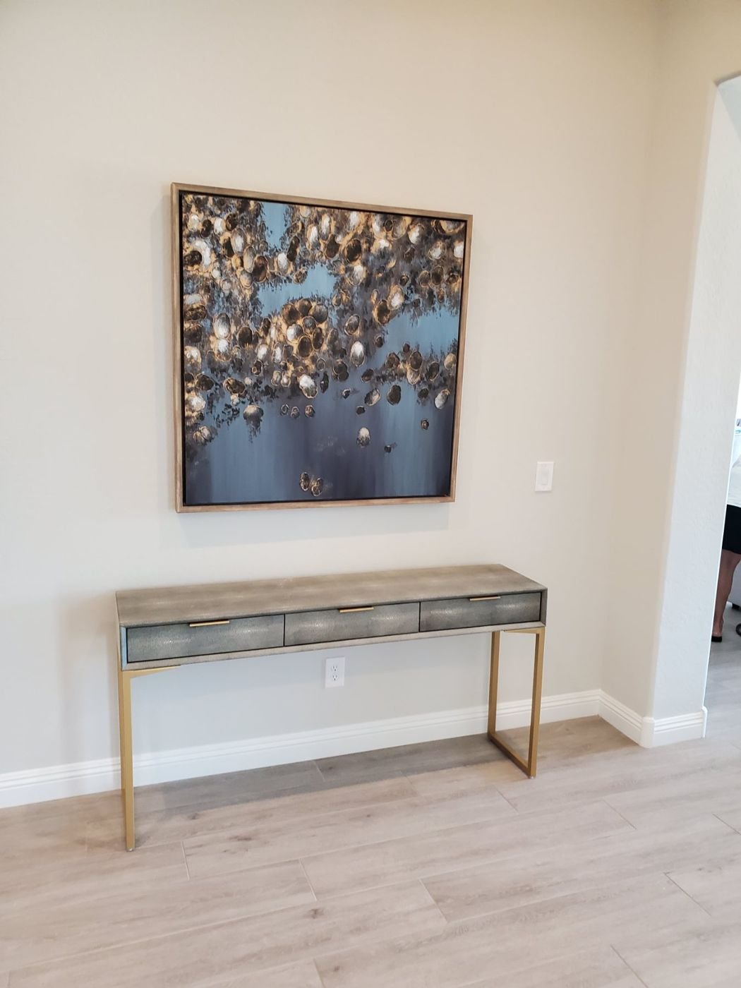 Large framed abstract art hung level above a gold console table in a Phoenix model home