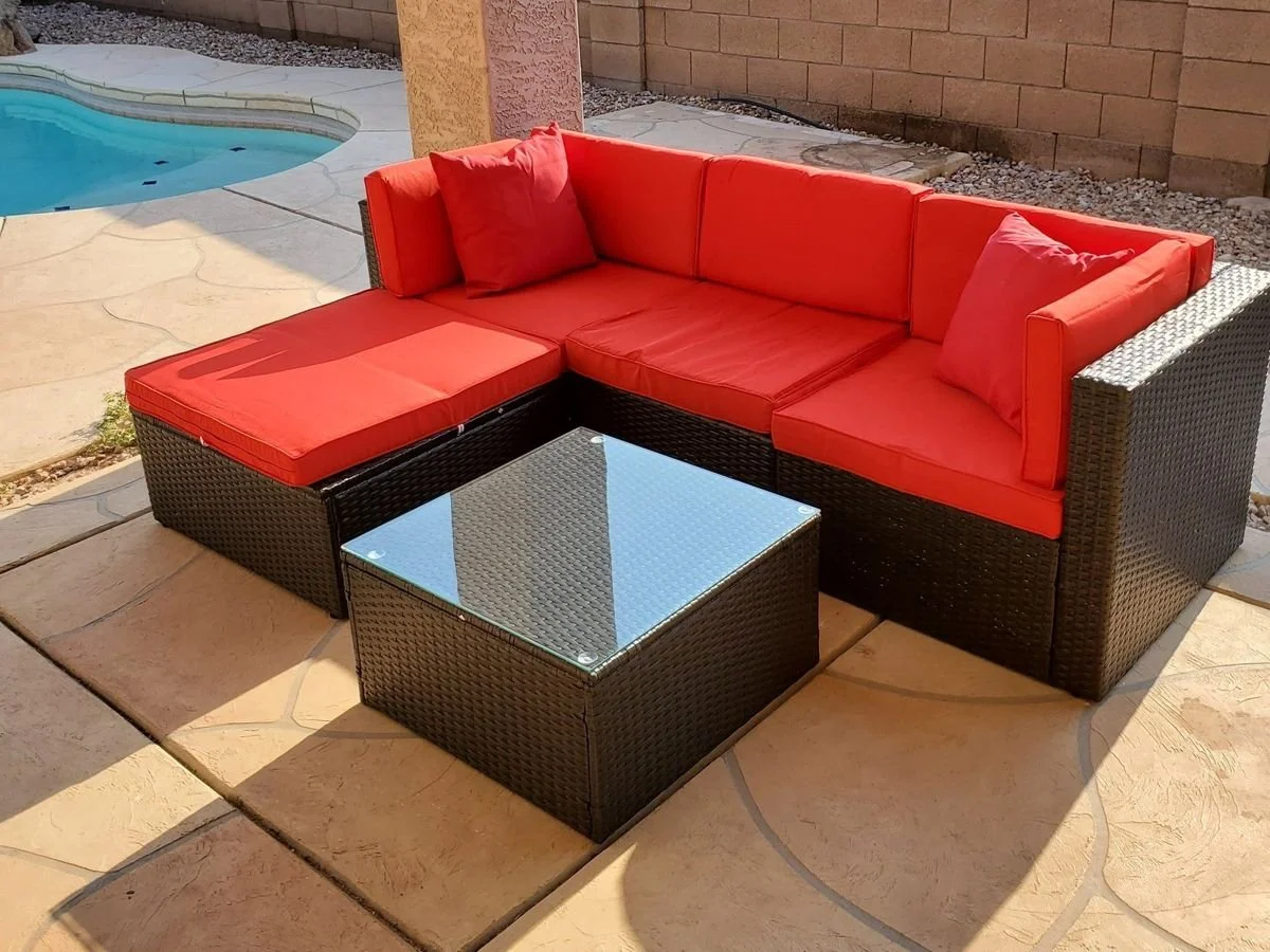 Red-cushion wicker sectional and glass coffee table assembled beside a Phoenix pool