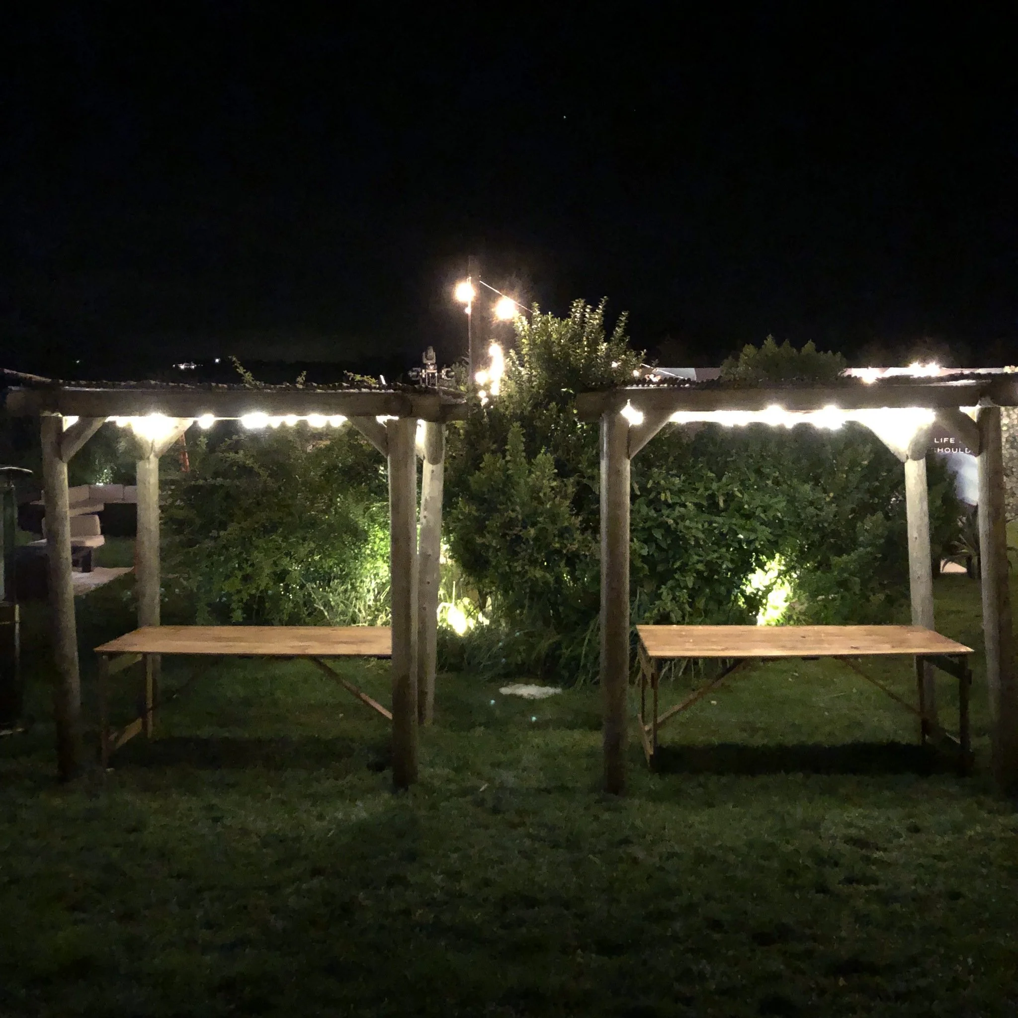 Evening beverage launch event with illuminated wooden tables outdoors
