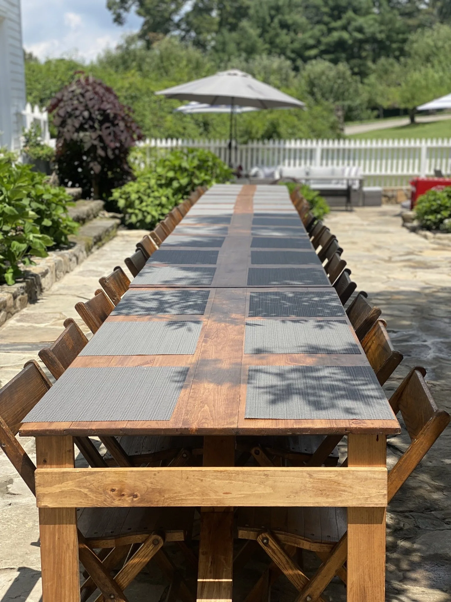 Patio lunch event featuring handmade folding farm tables with vintage wooden folding chairs in Armonk, New York