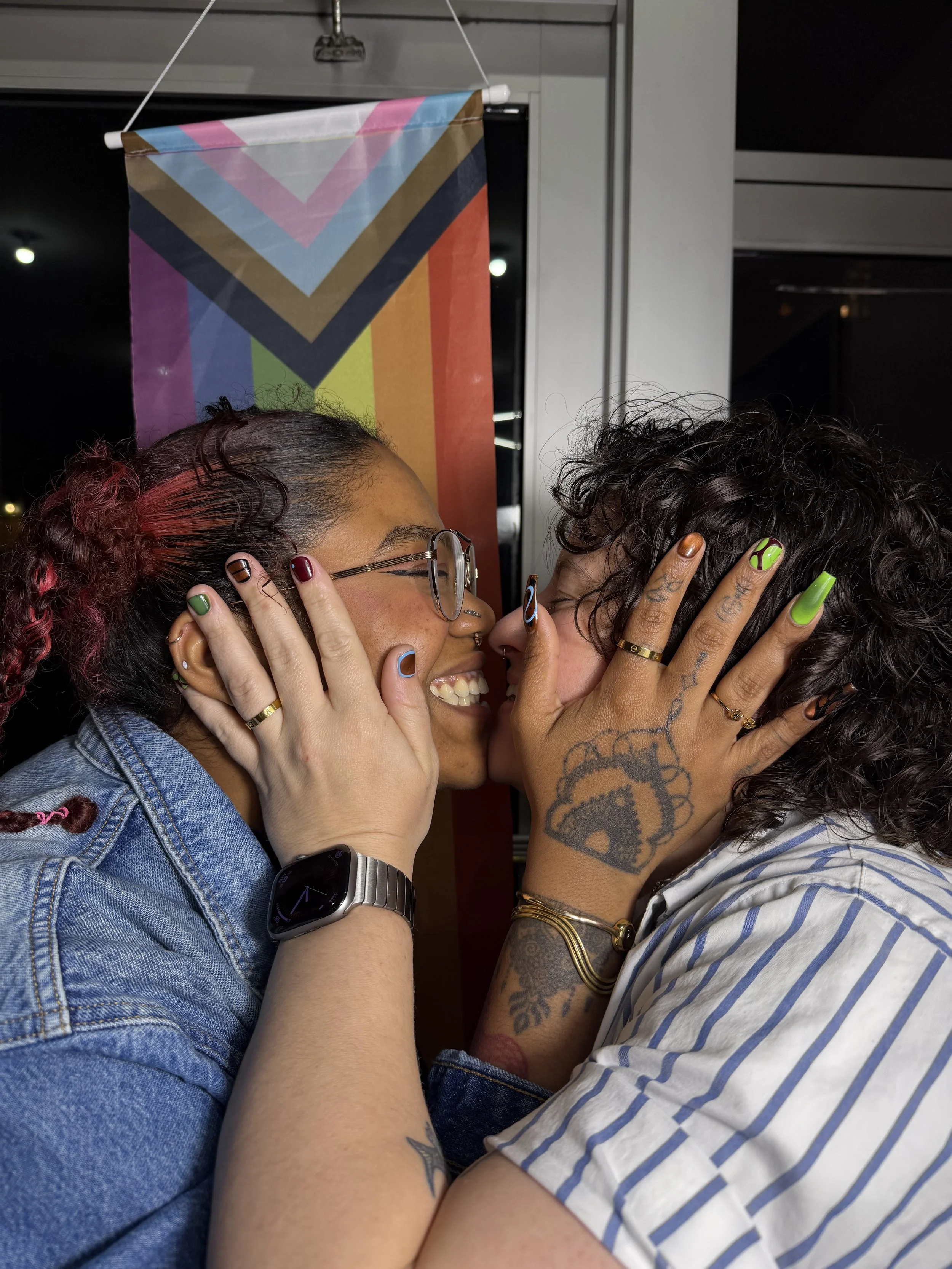 The Queerdos kissing in front of a Pride flag at Haus of Femme