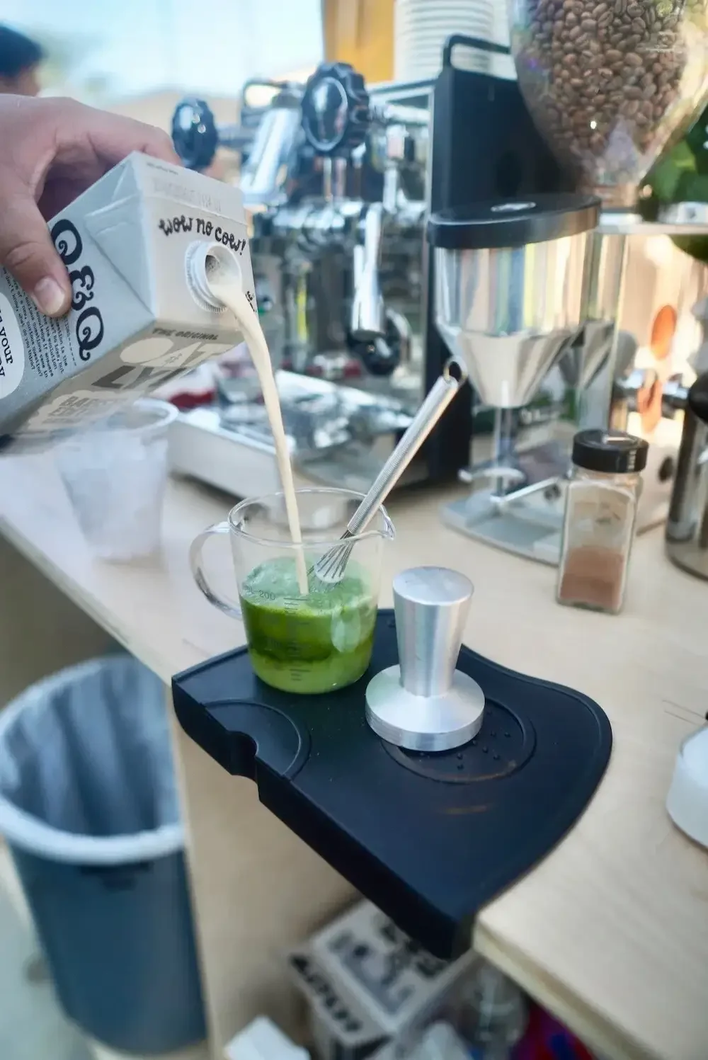 Barista pouring oat milk into a handcrafted matcha latte