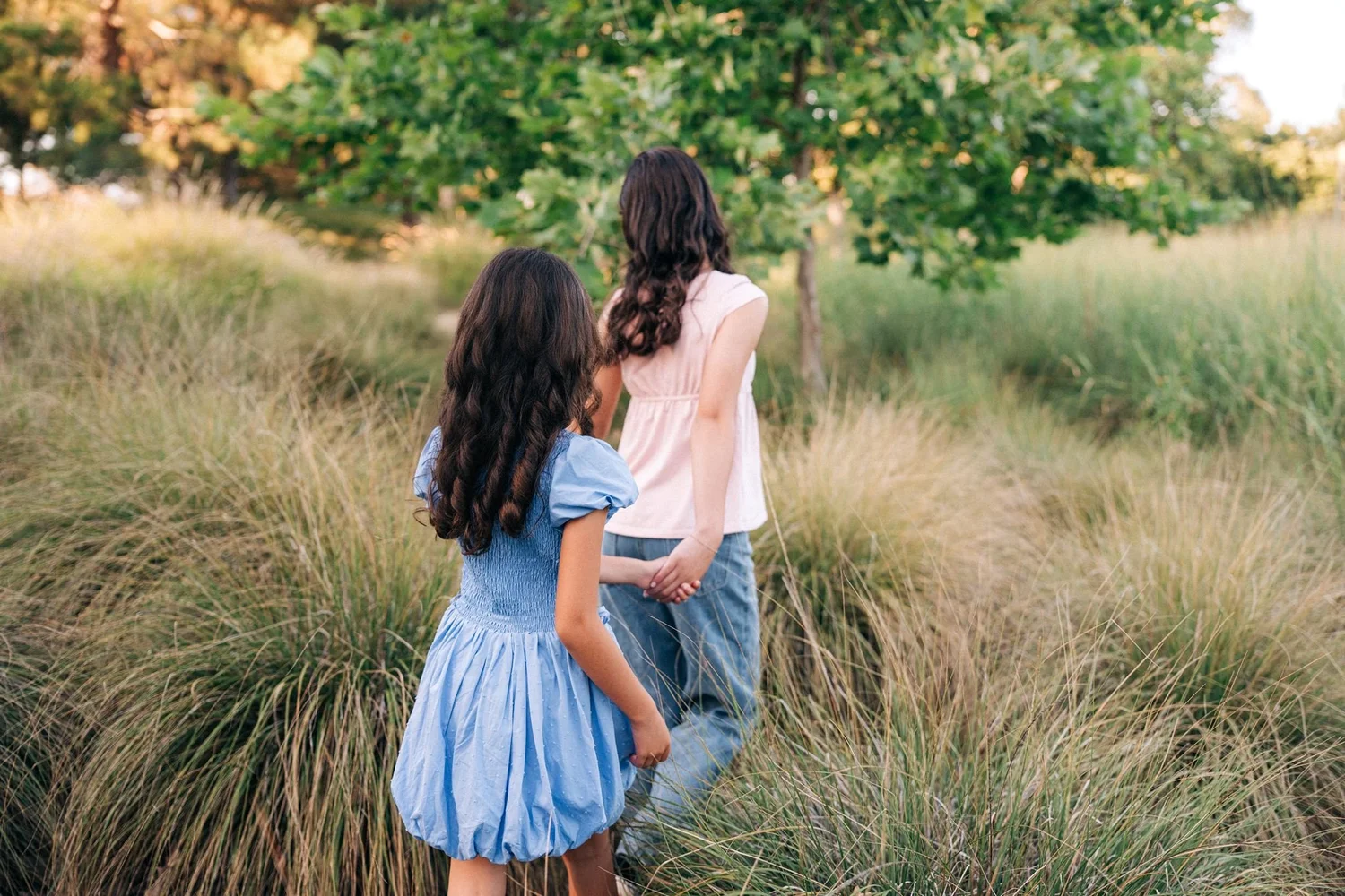 The two Slemmons sisters walking away hand in hand through the tall grass
