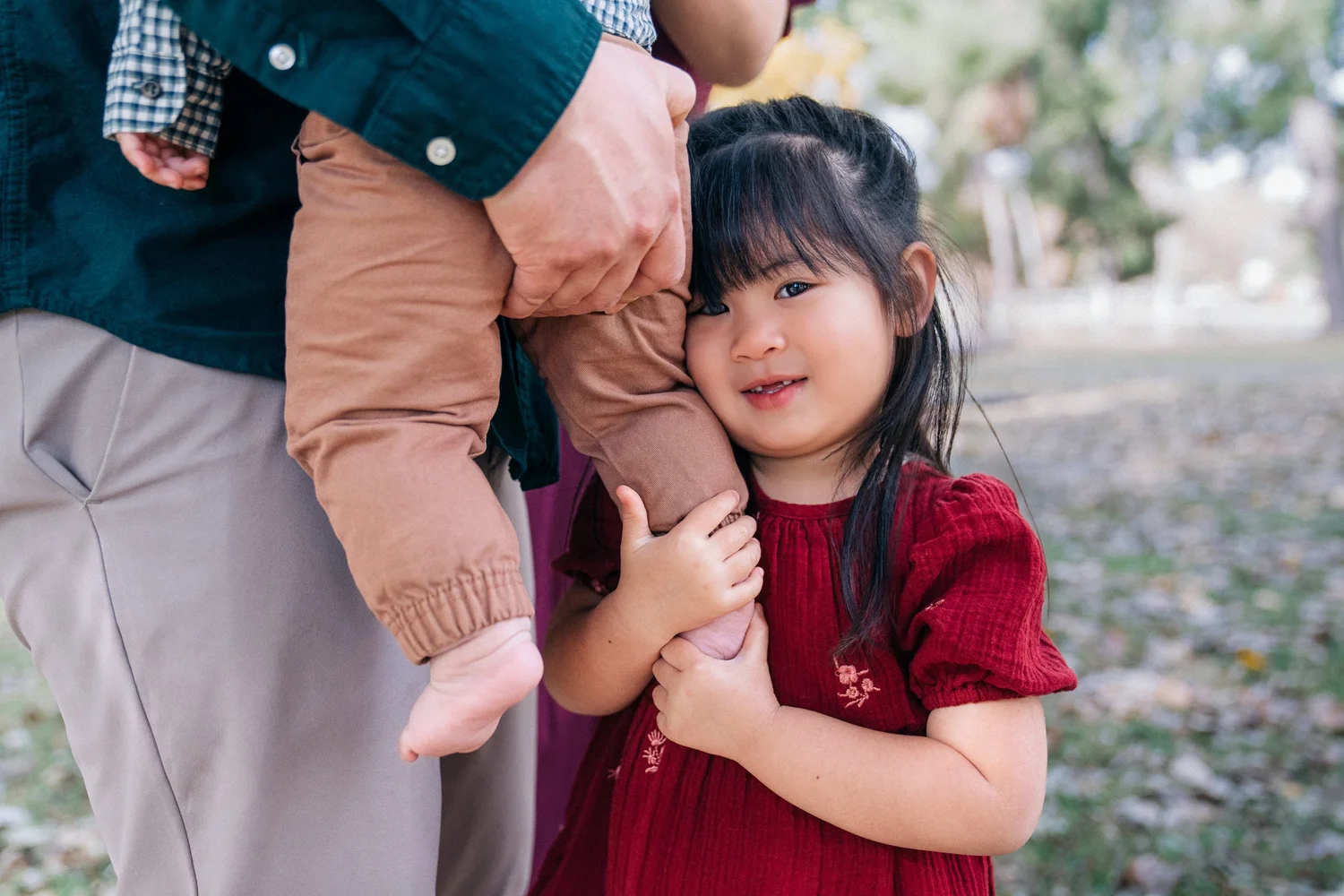 A little girl holding onto her baby brother while their dad carries him at Yorba Regional Park