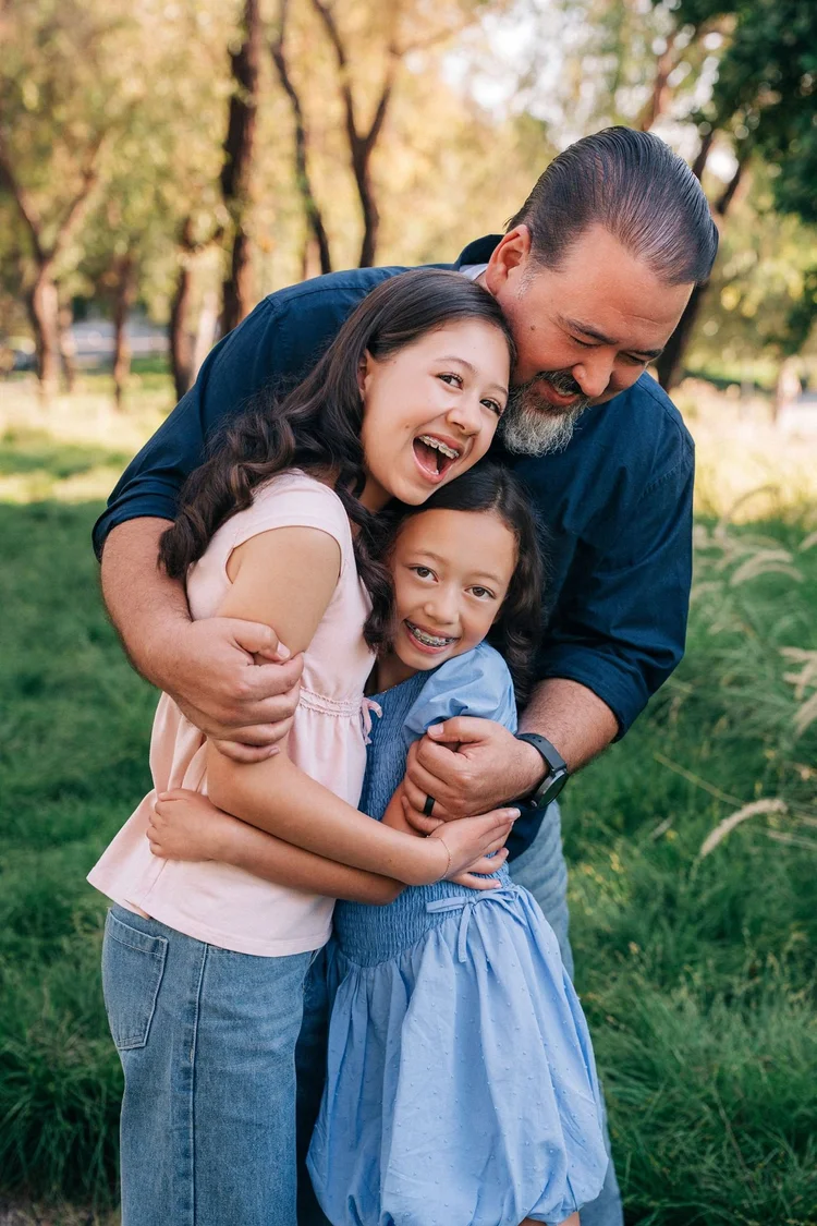 A dad hugging his two laughing daughters on the Jeffrey Open Space Trail in Irvine