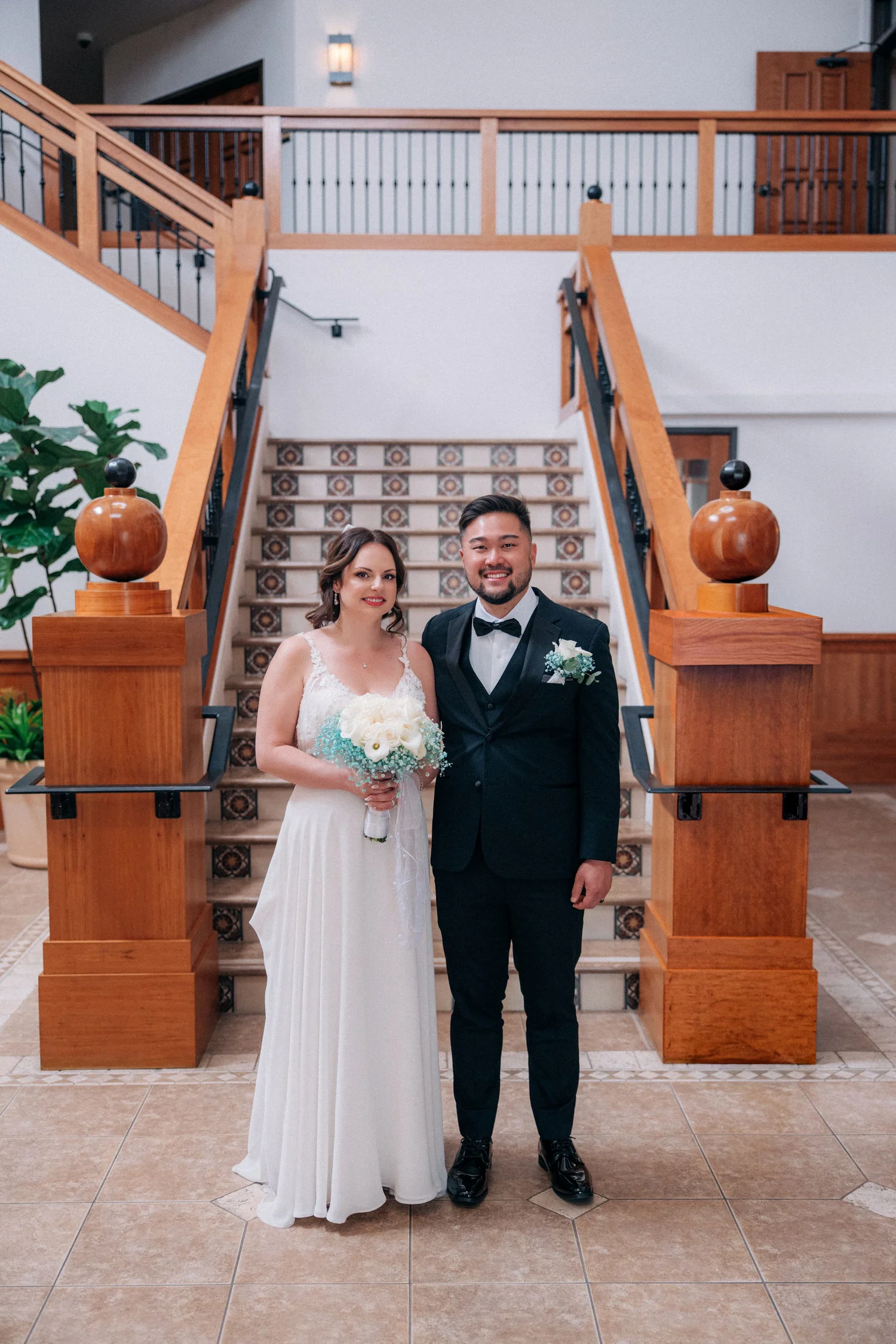 Jessica and Alex standing together at the foot of the tiled courthouse staircase, full length