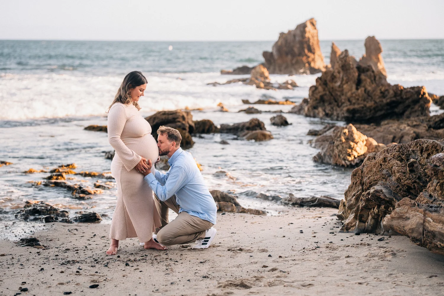 Maternity photo on the sand at Little Corona del Mar with the cliffs lit gold behind