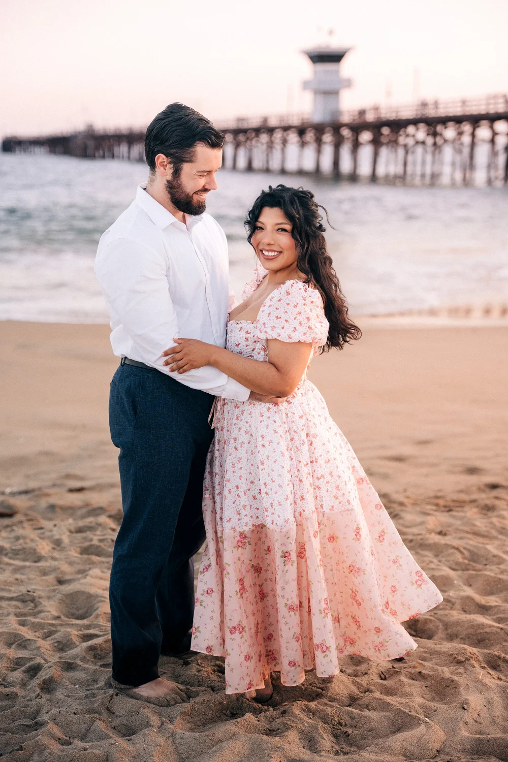 A family on the sand near the wooden Seal Beach Pier