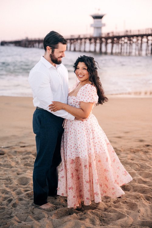 A couple on the sand near the wooden Seal Beach Pier