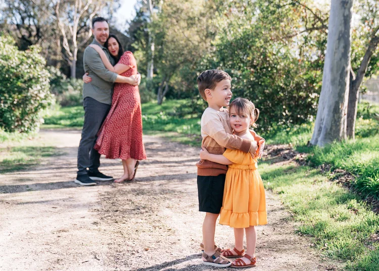 Two children hugging on a trail while their parents embrace behind them