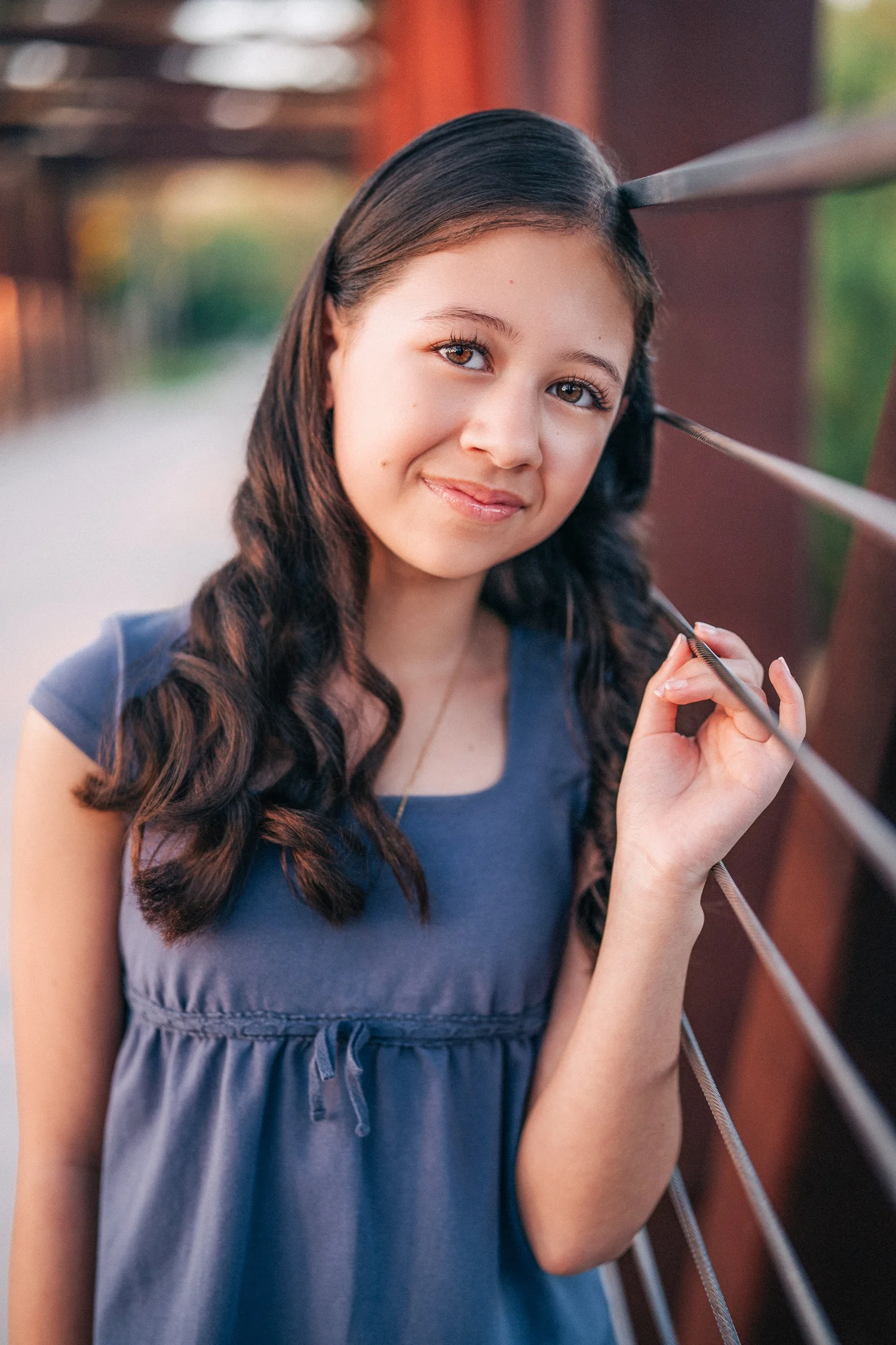 The older Slemmons daughter in a blue dress leaning against the bridge railing