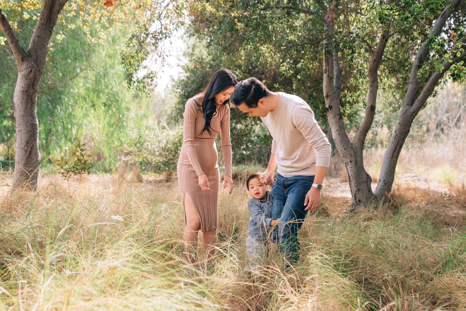 A family among the tall grass and trees at Yorba Regional Park in warm afternoon light