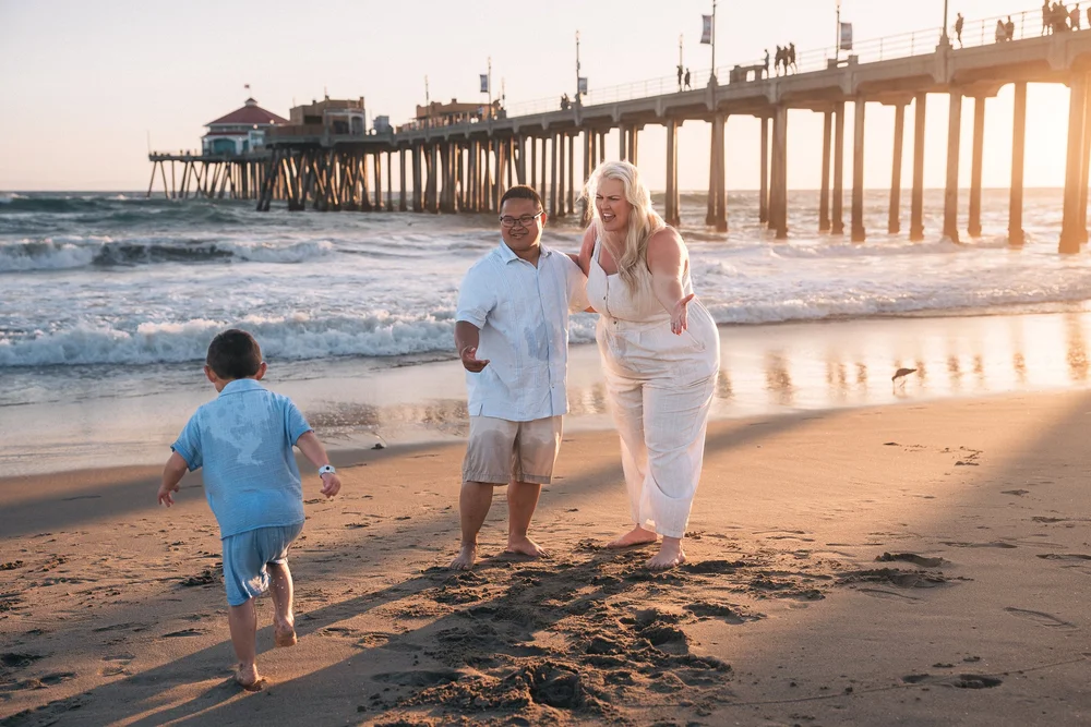 The boy running off across the sand while his mom, arms out, calls after him